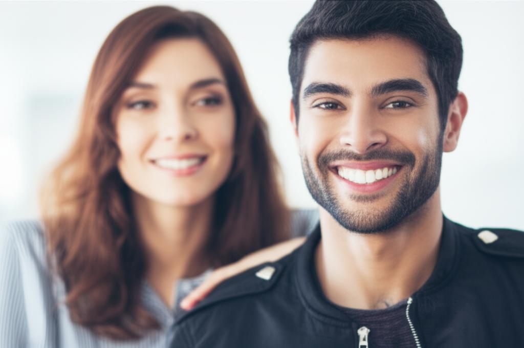 Man smiling confidently with partner in background